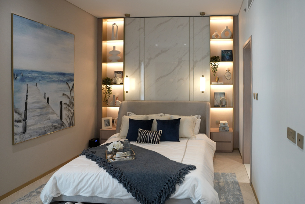 Beach Walk Residence Cozy bedroom featuring a neutral color palette, art, shelving, and a stylish bed with decorative pillows and throws.